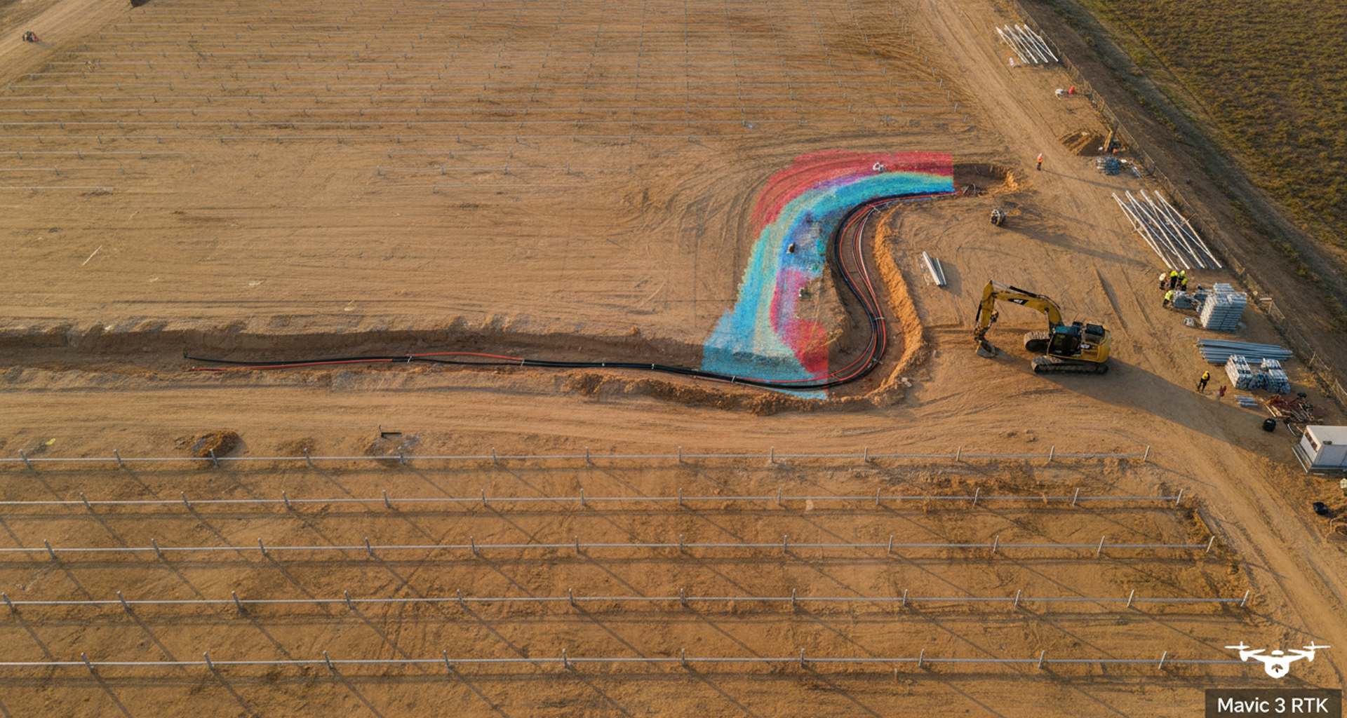 Aerial of a utility-scale Texas solar site mid-construction with RTK-graded pad rows and collector trenching corridor