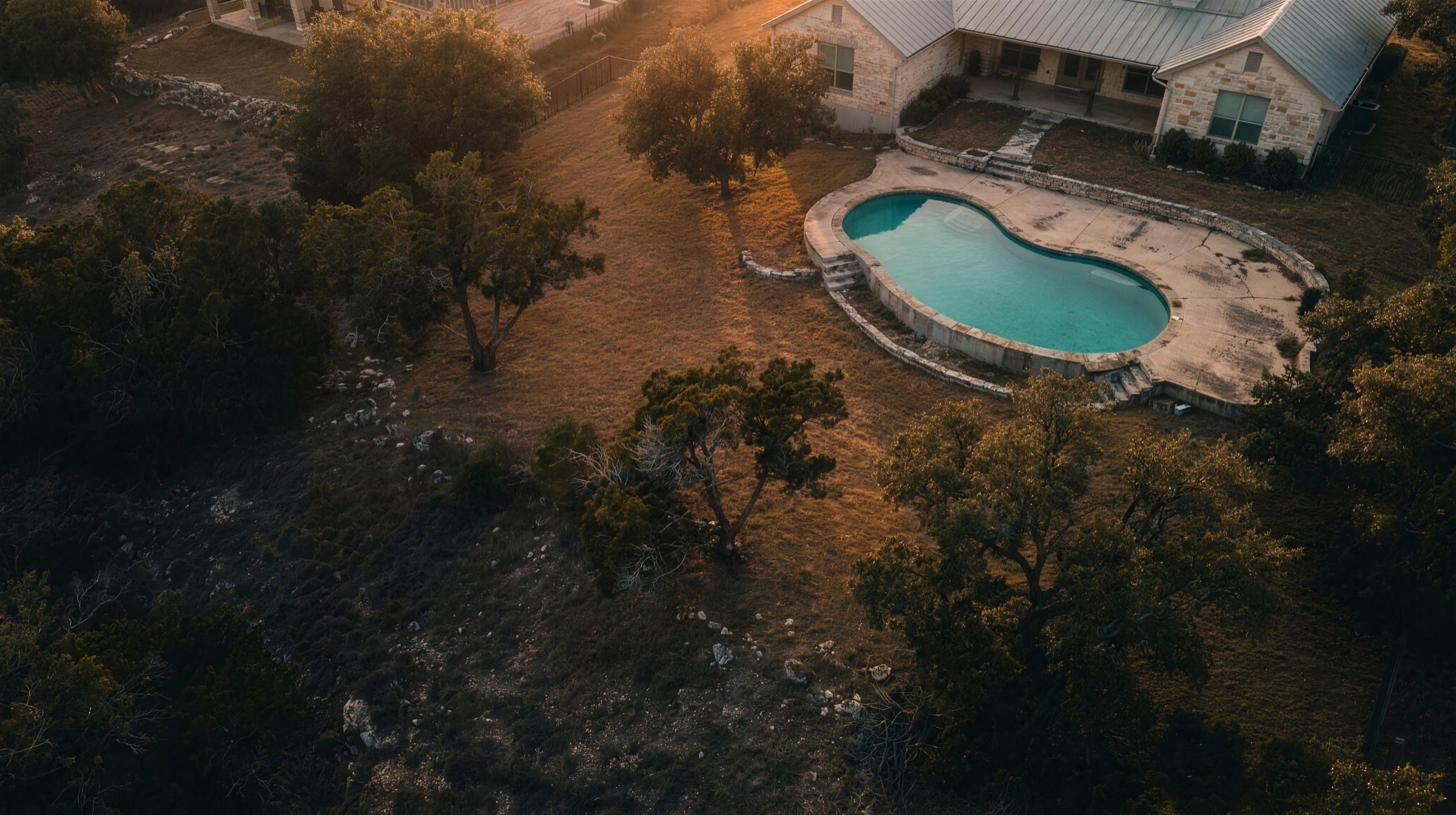 Aerial view of a backyard pool at the edge of Hill Country brush near Austin
